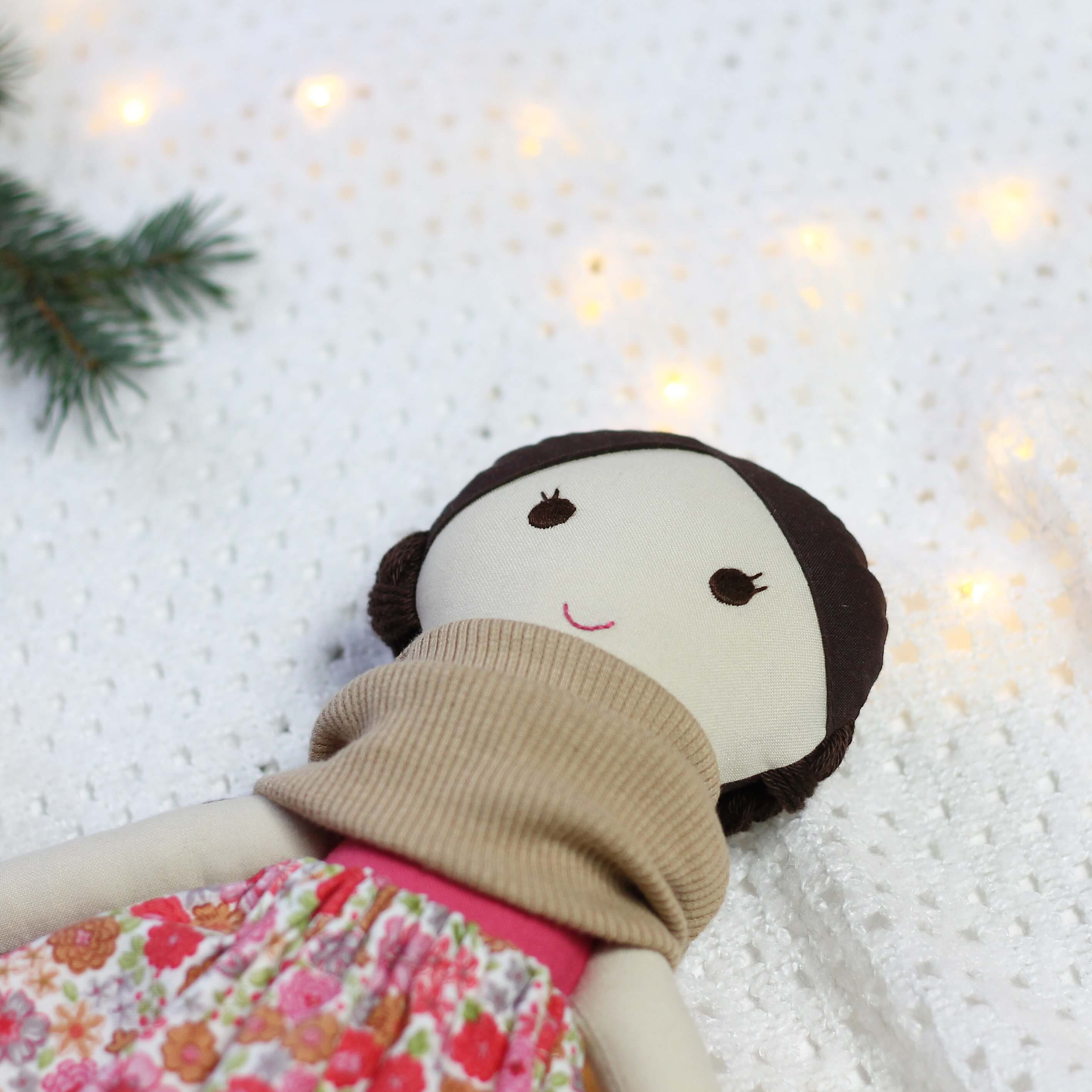 Ręcznie szyta lalka handmade w beżowym kominie i kwiecistej spódniczce na białym tle